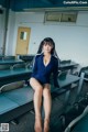 A woman sitting on a bench in a classroom.