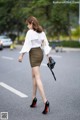 A woman walking down the street in a skirt and heels.