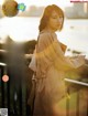 A woman in a trench coat standing on a bridge.