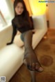 A woman sitting on a white couch wearing black stockings.