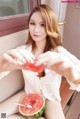 a woman sitting on a bench eating a slice of watermelon