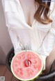 A woman holding a slice of watermelon with a spoon in it.