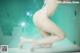 A woman in a white bikini sitting on the edge of a pool.