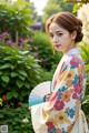 A woman in a kimono holding a fan in a garden.