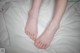 A woman's bare feet on a bed with white sheets.