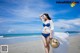 A woman in a blue bikini standing on a beach.