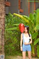 A woman in a blue and white dress holding a red balloon.