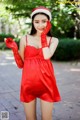 A woman in a red dress and a santa hat posing for a picture.