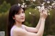 A woman holding a branch of a tree with white flowers.