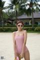 A woman in a pink swimsuit standing on a beach.