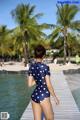 A woman in a polka dot swimsuit standing on a dock.