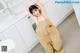 A woman in a beige jumpsuit posing in a kitchen.