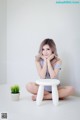 A woman sitting on the floor next to a white stool.