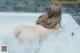 A woman is taking a bath in a bathtub filled with foam.