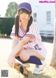 A young woman in a baseball uniform crouching on the ground.