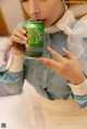 A woman in a blue shirt is holding a can of beer.