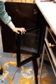 A woman is opening a small refrigerator in a kitchen.