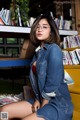 A woman sitting on a bench in front of a bookshelf.