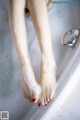 A woman's feet in a bathtub with foam on them.