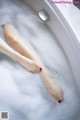 A woman's legs in a bathtub filled with foam.