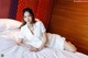 A woman in a white dress laying on a bed.