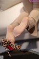 A close up of a woman's legs wearing leopard print shoes.