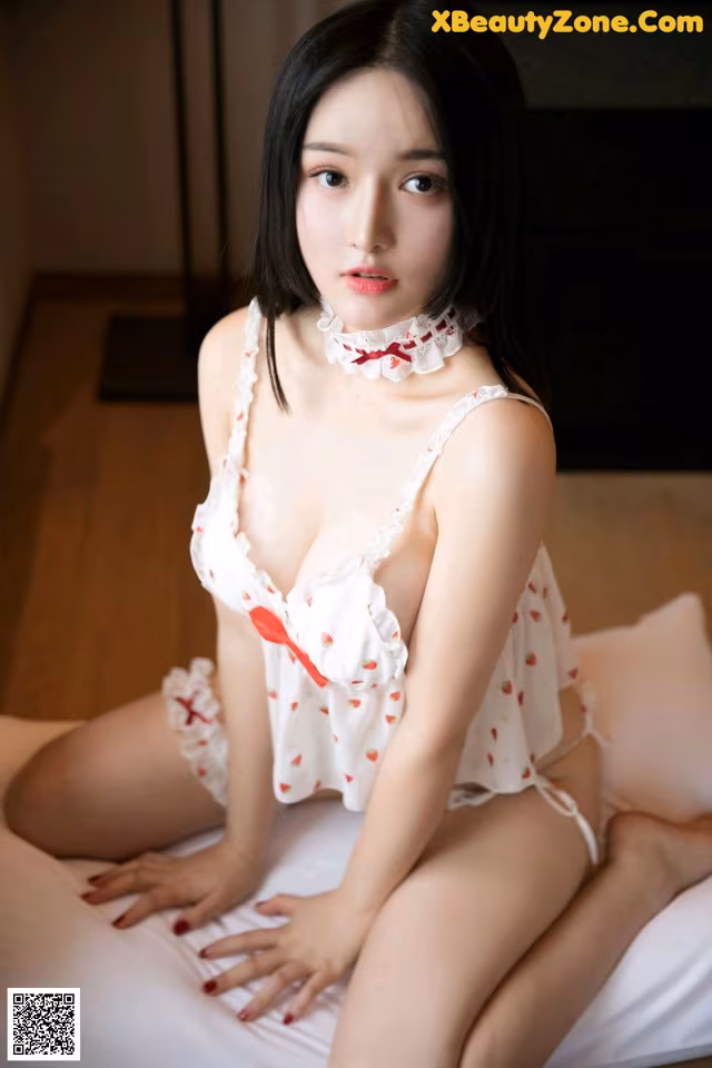 A woman in a white lingerie sitting on a bed.