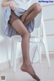 A woman sitting on a white chair wearing black stockings.