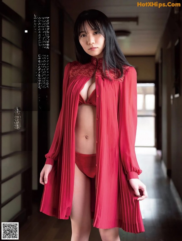 A woman in a red robe standing in a hallway.