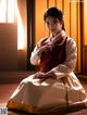 A woman in a traditional korean dress sitting on the floor.