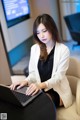 A woman sitting at a table using a laptop computer.