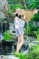 A woman standing in front of a waterfall wearing a hat.