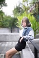 A woman in a denim jacket and black skirt posing for a picture.