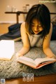 A woman laying on the floor reading a book.