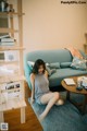 A woman sitting on the floor in front of a blue couch.