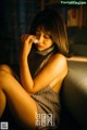 A woman sitting on a couch wiping her face with a tissue.