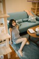 A woman sitting on a blue couch in a living room.