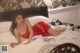 A woman in a red dress laying on a bed.