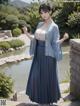 A woman in a blue kimono standing in front of a pond.