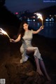 A woman sitting on a rock holding a sparkler.