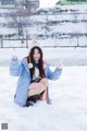 A woman sitting in the snow with her arms outstretched.