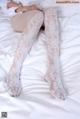 A woman laying on top of a bed wearing white stockings.