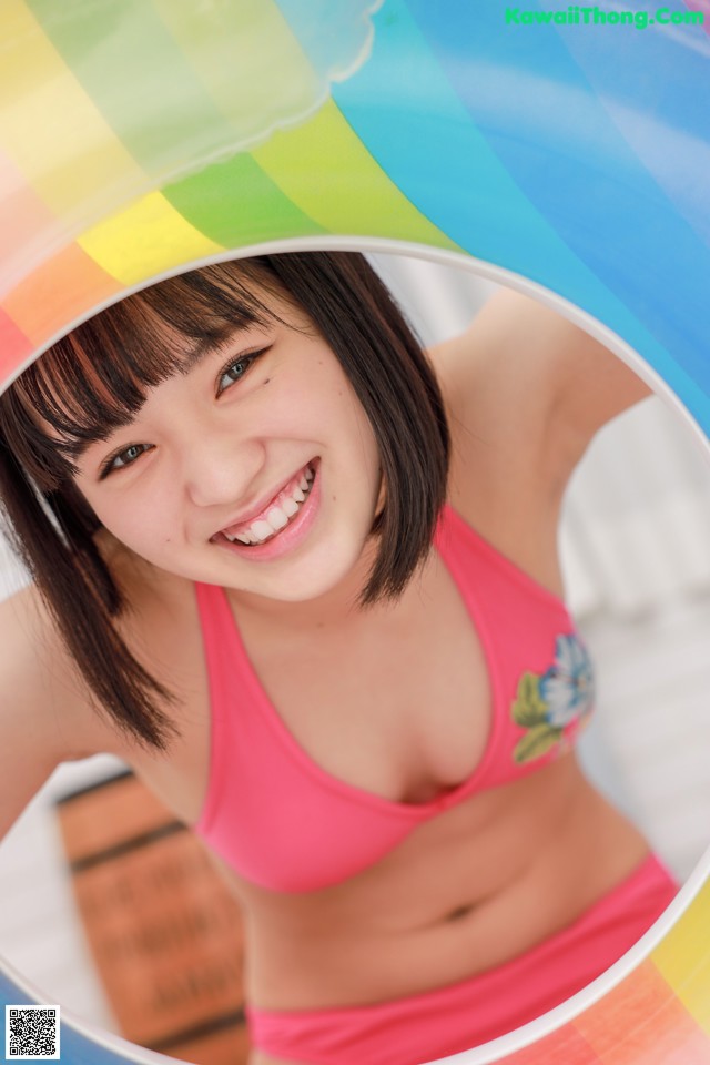 A young woman in a pink bikini smiling at the camera.