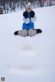 A woman sitting in the snow giving a thumbs up.