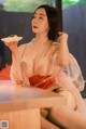 A woman in a kimono sitting at a table with a plate of food.