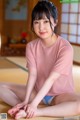 A woman in a pink shirt sitting on a tatami mat.