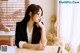 A woman sitting at a table with a book in front of her.