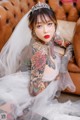 A woman with tattoos sitting on a couch wearing a veil.