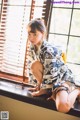 A woman in a kimono sitting on a window sill.