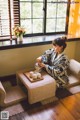 A woman sitting on a couch in front of a window.